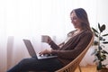 Happy millennial girl surfing on laptop and enjoying coffee