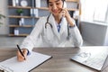 Happy millennial hindu lady doctor in uniform talking by phone with patient in office interior, cropped Royalty Free Stock Photo