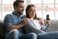 Happy millennial husband and wife using mobile phone