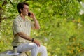 Happy millennial man sitting at park, talking on phone Royalty Free Stock Photo