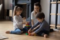 Happy millennial mother playing toys with little kids. Royalty Free Stock Photo