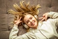 Happy millennial teen girl lying on comfortable sofa have fun moving enjoying listening music in earphones. Cute Young woman Royalty Free Stock Photo