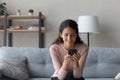 Happy millennial woman browsing internet on cellphone at home