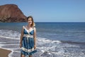 Happy millennial woman wearing a blue paisley dress while enjoying a beautiful day on La Tejita beach, Tenerife, Canary Islands Royalty Free Stock Photo