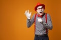 Happy mime man in red hat, white gloves and striped t-shirt on blank orange background