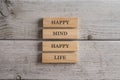 Happy mind happy life sign written on a stack of wooden pegs