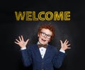 Happy mischievous kid and Welcome inscription on chalkboard background