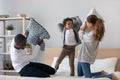 Happy mixed ethnicity parents son playing pillow fight on bed Royalty Free Stock Photo