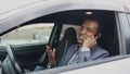 Happy mixed race businessman talking phone while sitting inside his car outdoors Royalty Free Stock Photo