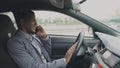 Happy mixed race businessman talking phone while sitting inside his car outdoors Royalty Free Stock Photo