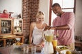 Happy mixed race couple making smoothies, using blender