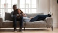 Happy mixed race couple relax on couch using smartphone Royalty Free Stock Photo