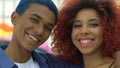 Happy mixed-race couple of teens hugging and smiling on camera, subculture