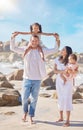 A happy mixed race family of four enjoying fresh air at the beach. Hispanic couple bonding with their daughters while Royalty Free Stock Photo