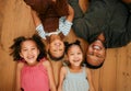 A happy mixed race family of four relaxing and lying on the lounge floor together. Loving black single parent bonding Royalty Free Stock Photo