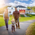 Happy Mixed Race Family in Front of Home and Sold For Sale Sign Royalty Free Stock Photo