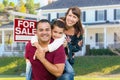 Happy Mixed Race Family In Front of House and For Sale Real Estate Sign Royalty Free Stock Photo