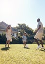 Happy mixed race family playing soccer outside in the garden at home. Parents enjoying kicking a ball with their son Royalty Free Stock Photo