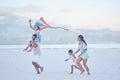 Happy mixed race family running along the beach with a kite. Carefree parents and two children enjoying fun activity Royalty Free Stock Photo