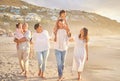 Happy mixed race family of six walking on the beach. Two cute sisters enjoying the sand and sea with their mom, dad Royalty Free Stock Photo