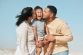 Happy mixed race family standing on the beach. Loving parents kissing adorable little son on the cheeks showing love and Royalty Free Stock Photo