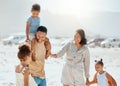 Happy mixed race family with three children laughing and talking while walking along the beach together. Loving parents Royalty Free Stock Photo