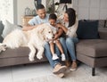 A happy mixed race family of three relaxing on the sofa with their dog. Loving black family being affectionate with a Royalty Free Stock Photo