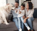A happy mixed race family of three relaxing on the sofa with their dog. Loving black family being affectionate with a Royalty Free Stock Photo