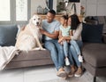 A happy mixed race family of three relaxing on the sofa with their dog. Loving black family being affectionate with a Royalty Free Stock Photo