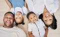 Happy mixed race family with two children lying on floor together and bonding at home from above. Little brother and Royalty Free Stock Photo