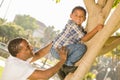 Happy Mixed Race Father Helping Son Climb a Tree