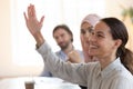 Happy mixed race female employee raising hand, asking question. Royalty Free Stock Photo