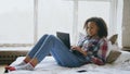 Happy mixed race girl having video chat with friends using laptop camera while lying on bed Royalty Free Stock Photo