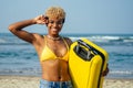 Happy mixed race hispanic brazil woman in yellow swimming suit bra and demin shorts having fun at beach with ribbon