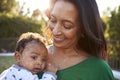 Happy African American middle aged grandmother holding her three month old grandson in the garden, close up, head and shoulders