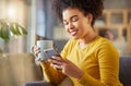 Happy mixed race woman drinking a cup of coffee and typing a message on a phone at home. One content hispanic female Royalty Free Stock Photo