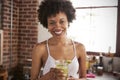 Happy mixed race woman holding smoothie, looking to camera