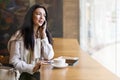 Happy woman sitting at cafe waiting departure flight in airport terminal talking use smartphone Royalty Free Stock Photo