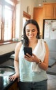 Happy mixed race woman smiling while using smart phone at home. Woman reading text message or chatting on social media Royalty Free Stock Photo