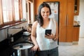 Happy mixed race woman smiling while using smart phone at home. Woman reading text message or chatting on social media