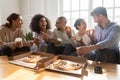 Happy mixed race young colleagues enjoying eating ordered pizza. Royalty Free Stock Photo