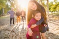 Happy Mixed Race Young Girl Sisters Outdoors with Family Behind