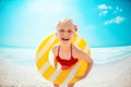 Happy modern child with yellow inflatable lifebuoy on beach