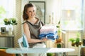 Happy modern female with iron, ironing board and clothes