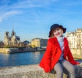 Happy modern girl in red coat on embankment in Paris, France Royalty Free Stock Photo