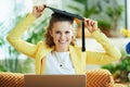 Happy modern housewife with graduation cap and laptop