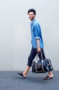 Happy modern man walking and holding travel bag