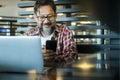 Happy modern mature man at work in coworking workplace alternative office using laptop computer and mobile phone to communicate. Royalty Free Stock Photo