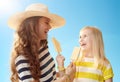 Happy mother and daughter eating ice cream against blue sky Royalty Free Stock Photo