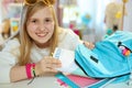 Happy modern pupil packing for school at home in sunny day
